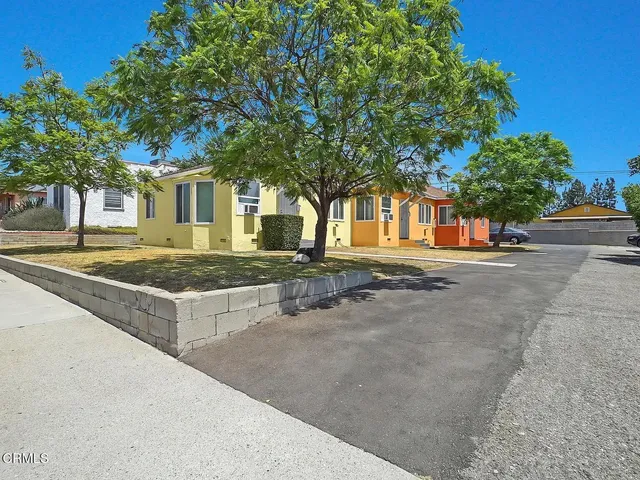 a front view of a house with large trees