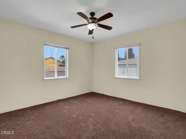 an empty room with windows and ceiling fan