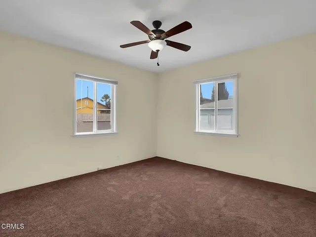 an empty room with windows and ceiling fan