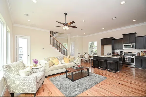 a living room with furniture kitchen view and a wooden floor