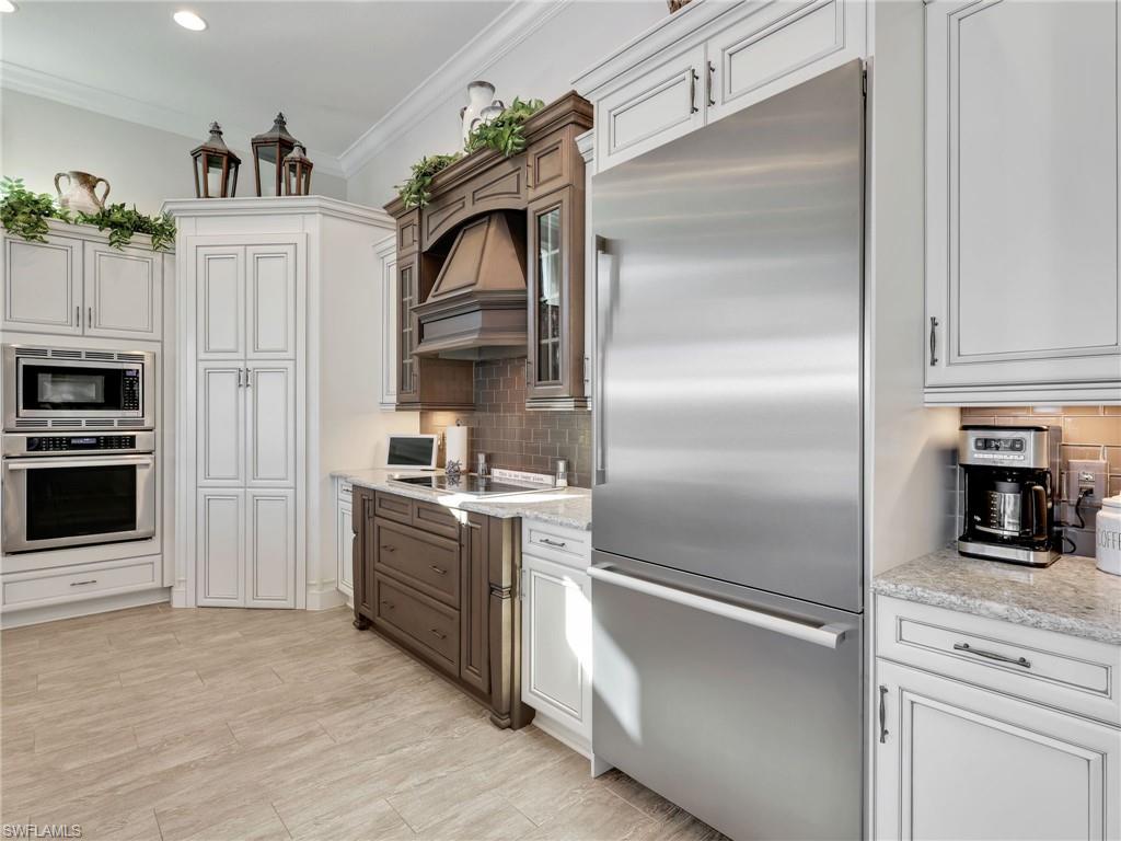 12757 Dundee Lane Naples, FL 34120 - Photo 15 of 48 a kitchen with white cabinets and stainless steel appliances