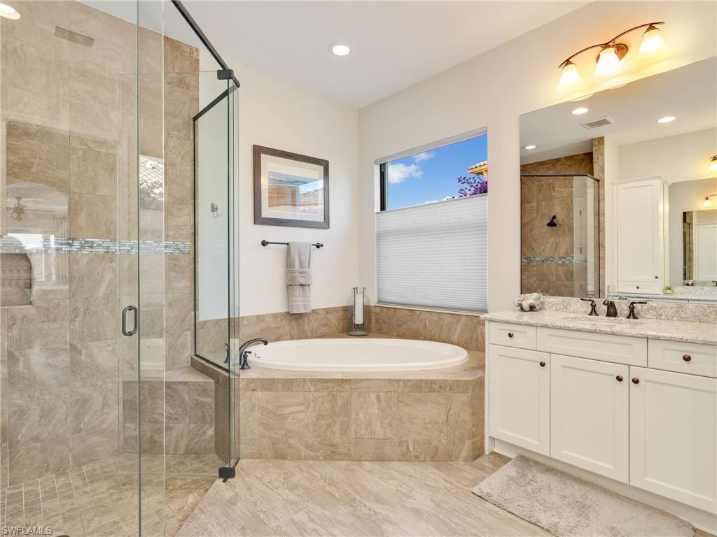 12757 Dundee Lane Naples, FL 34120 - Photo 20 of 48 a spacious bathroom with a granite countertop sink a mirror a bathtub and shower