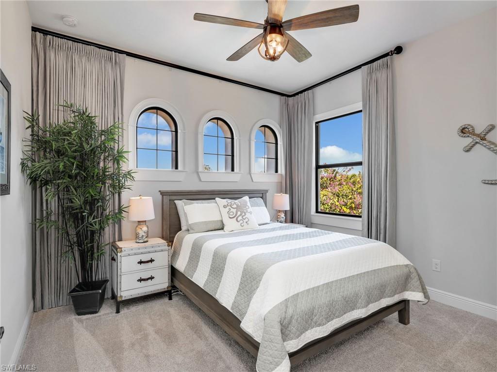 12757 Dundee Lane Naples, FL 34120 - Photo 21 of 48 a bedroom with a bed and a chandelier