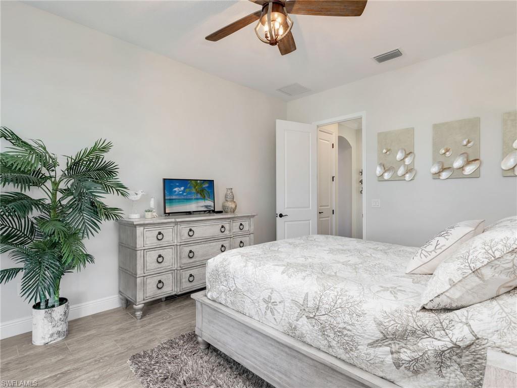 12757 Dundee Lane Naples, FL 34120 - Photo 31 of 48 a bedroom with a bed and a chandelier