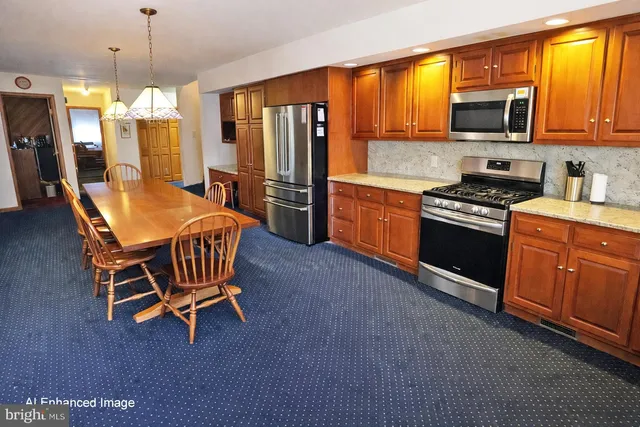 a kitchen with stainless steel appliances granite countertop a stove top oven a refrigerator a sink a dining table and chairs with wooden floor