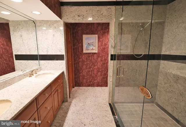 a bathroom with a granite countertop sink a mirror and shower