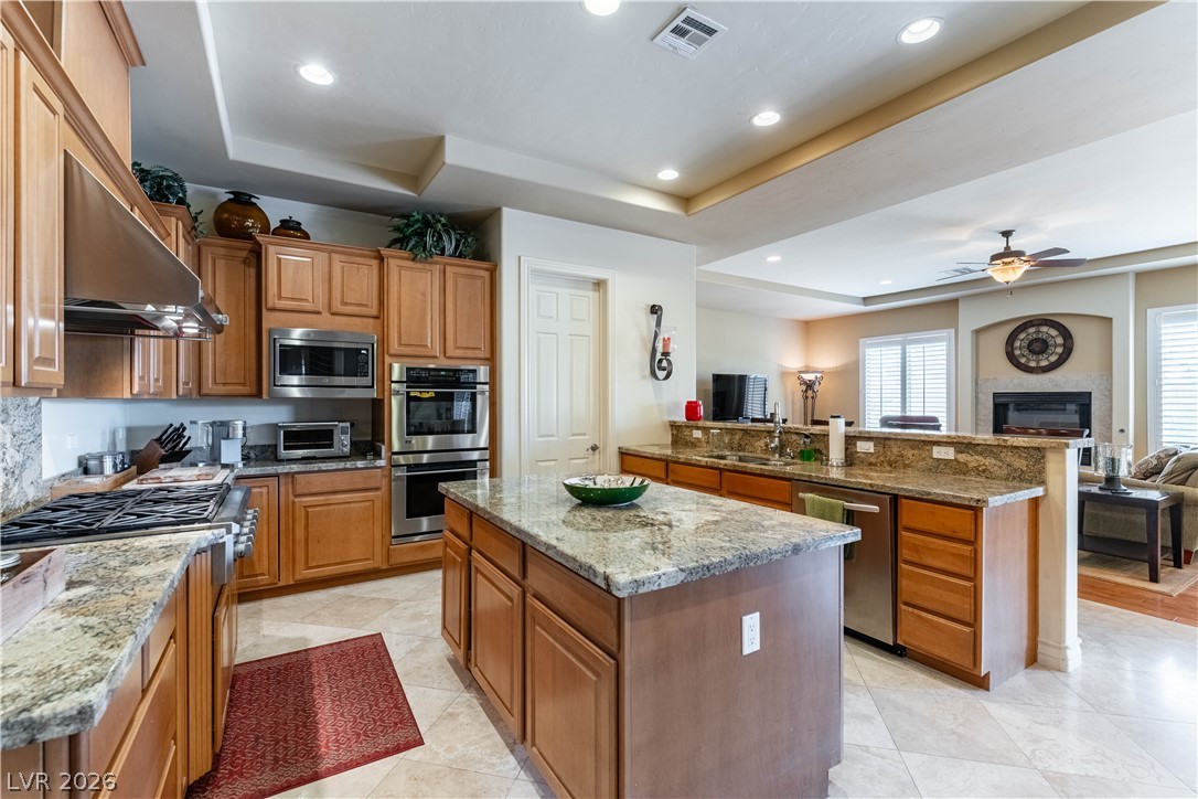 3661 Riley Ann Avenue Las Vegas, NV 89139 - Photo 14 of 42 Culinary delights await in this gourmet kitchen, flowing seamlessly into a cozy living area with a fireplace.