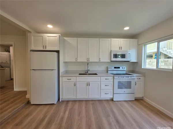 a kitchen with stainless steel appliances granite countertop a refrigerator a stove a sink and white cabinets with wooden floor