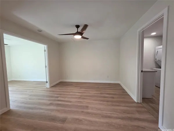 a view of empty room with wooden floor and ceiling fan