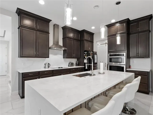 a kitchen with stainless steel appliances kitchen island granite countertop a refrigerator a sink a stove and oven