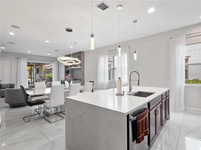 a large kitchen with stainless steel appliances a sink and living room view