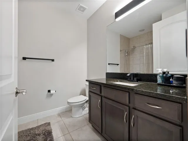 a bathroom with a granite countertop sink a toilet and a mirror