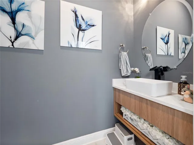 a bathroom with a sink a mirror and painting on the wall