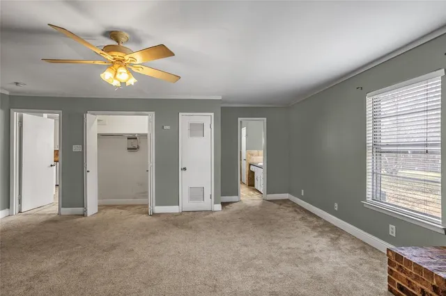an empty room with windows and a chandelier fan