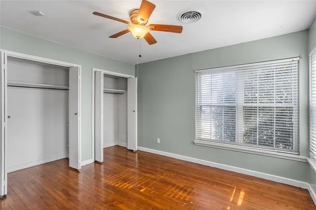 a view of an empty room with window and wooden floor