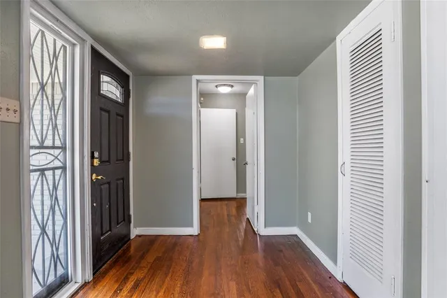 a view of a hallway with wooden floor and a bathroom