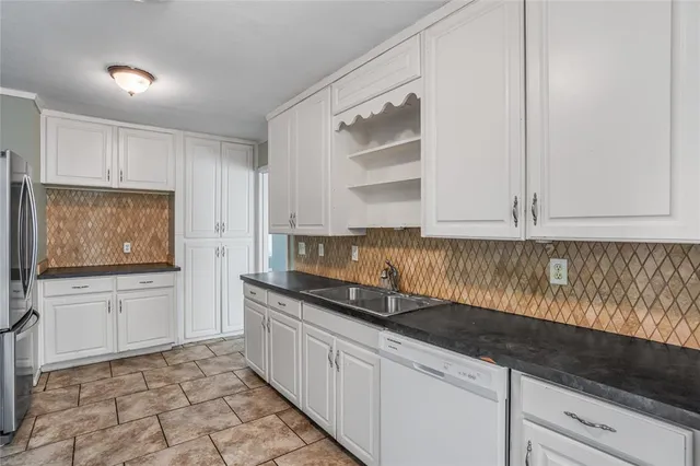 a kitchen with granite countertop a sink a stove and cabinets