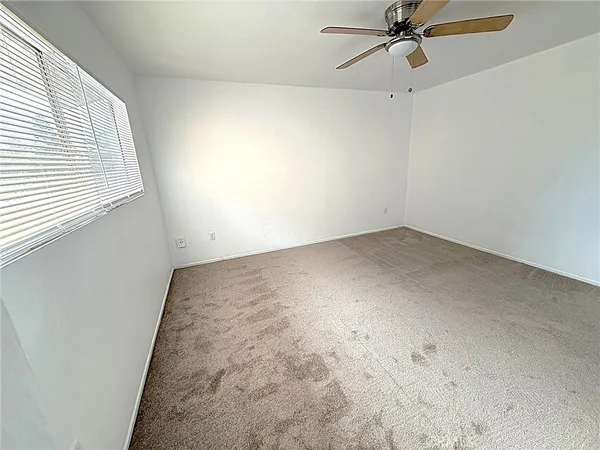 an empty room with a window and a fan