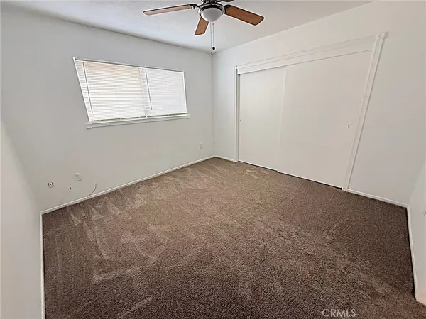 an empty room with a window and a ceiling fan