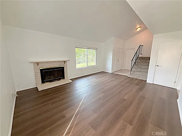 an empty room with wooden floor fireplace and windows