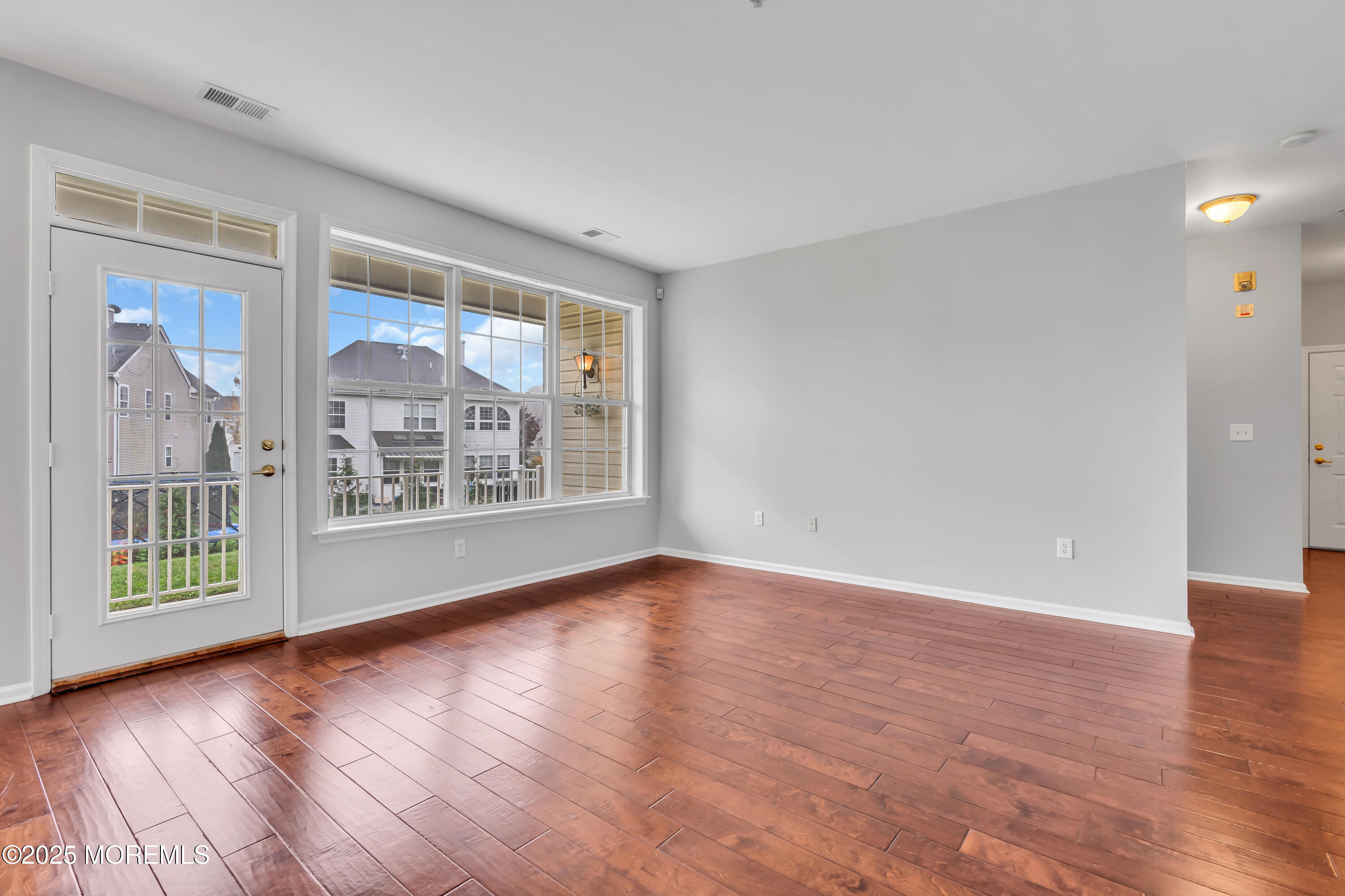 694 St Andrews Place Manalapan, NJ 07726 - Photo 5 of 26 a view of an empty room with wooden floor and a window