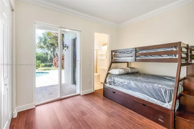 a bedroom with a bed and large window with wooden floor