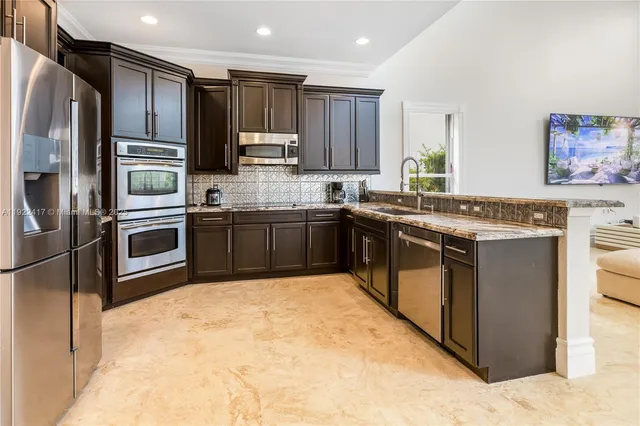 a kitchen with stainless steel appliances granite countertop a stove top oven sink and refrigerator