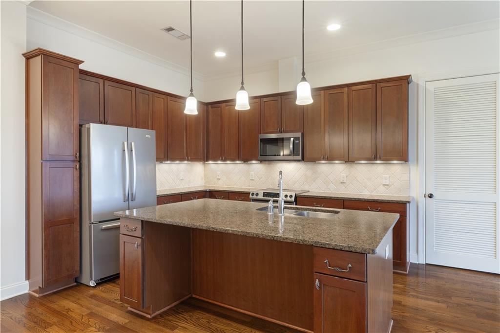 360 Chambers Street, Unit 208 Woodstock, GA 30188 - Photo 20 of 46 a kitchen with kitchen island granite countertop stainless steel appliances a sink a refrigerator a sink and cabinets