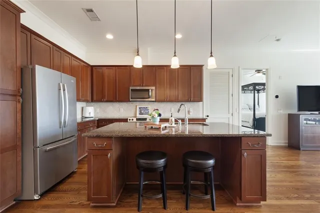 a kitchen with stainless steel appliances granite countertop a sink a stove a refrigerator and island with wooden floor