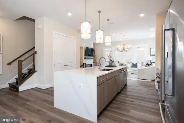 a large white kitchen with a large island oven a stove a sink and a refrigerator
