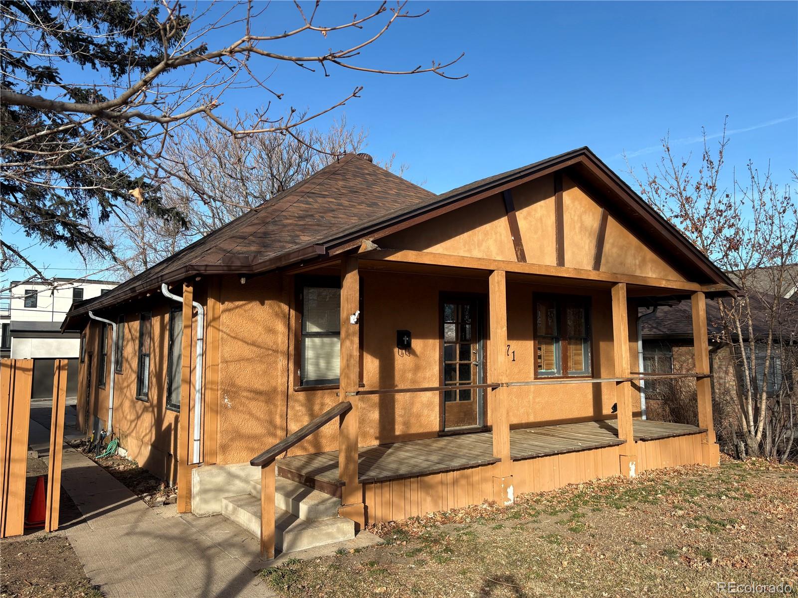 a view of a house with wooden walls and a tree
