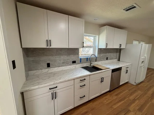 a kitchen with a sink a stove a refrigerator and cabinets