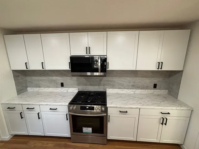 a kitchen with stainless steel appliances granite countertop white cabinets and a stove a oven with white countertops
