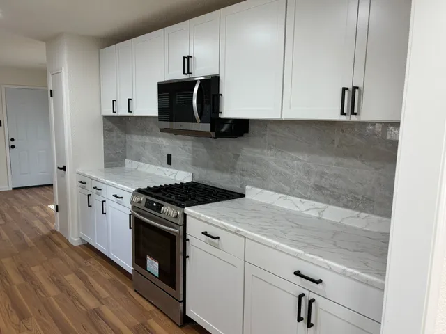 a kitchen with granite countertop white cabinets and white appliances