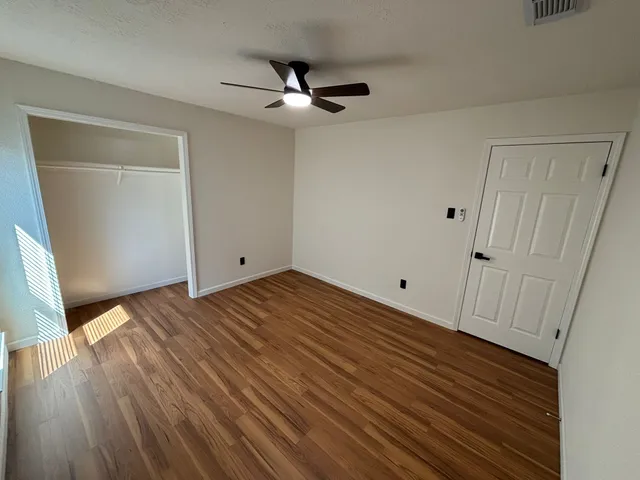 a view of empty room with wooden floor and window