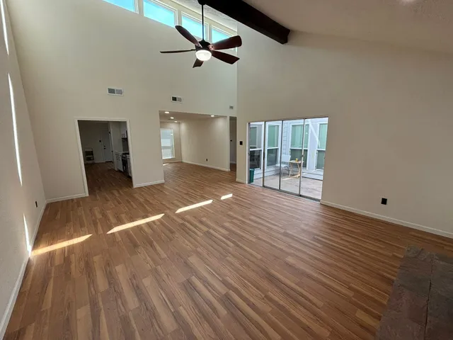 a view of a room with wooden floor ceiling fan and window