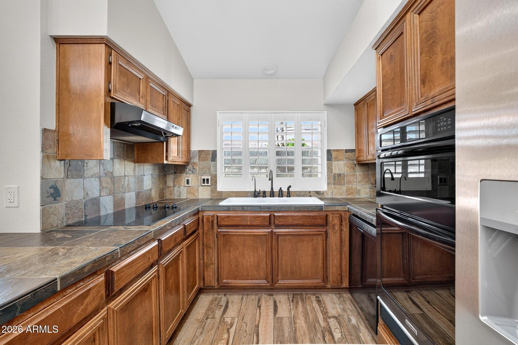 4615 East Monte Way Phoenix, AZ 85044 - Photo 7 of 35 a kitchen with stainless steel appliances granite countertop a sink and wooden cabinets
