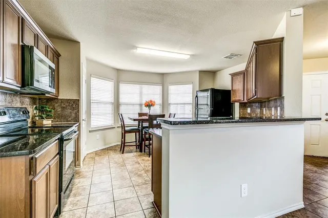 a kitchen with stainless steel appliances granite countertop a stove top oven a sink a dining table and chairs with wooden floor