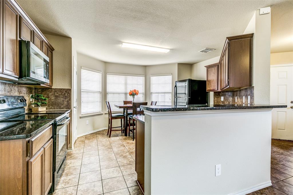 1774 Pioneer Way Lancaster, TX 75146 - Photo 12 of 23 a kitchen with stainless steel appliances granite countertop a stove top oven a sink a dining table and chairs with wooden floor