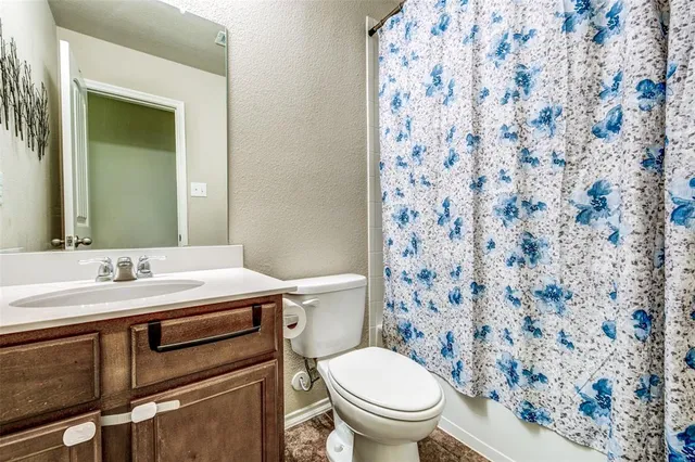 a bathroom with a granite countertop toilet sink and mirror