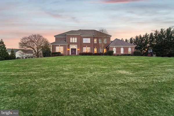 a view of a big house with a big yard and large trees