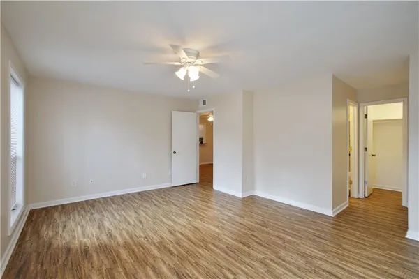 a view of empty room with wooden floor and fan