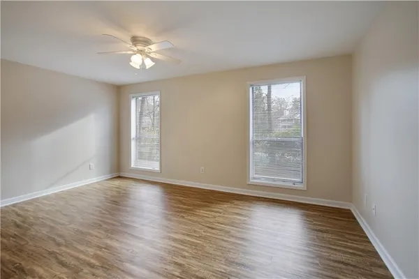 a view of an empty room with wooden floor and a window