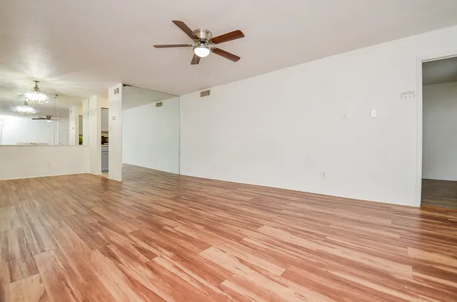 an empty room with wooden floor and a ceiling fan
