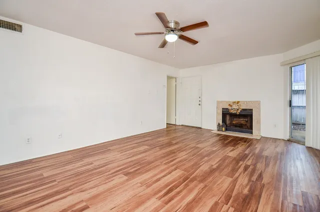 a view of empty room with wooden floor and ceiling fan