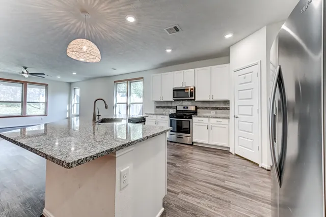 a kitchen with stainless steel appliances granite countertop a sink a stove and refrigerator