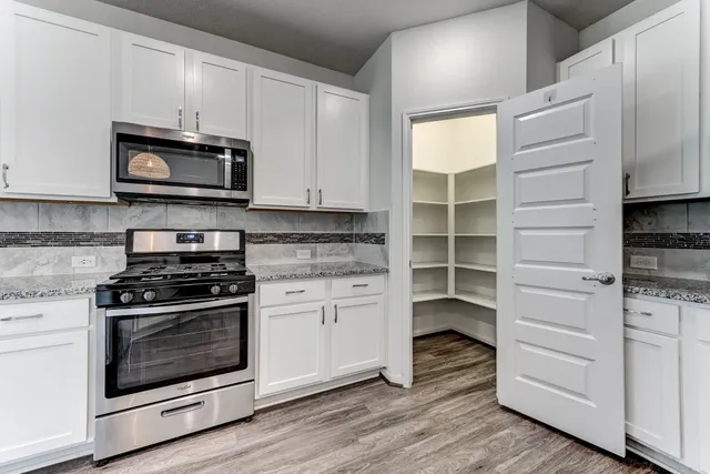 a kitchen with stainless steel appliances white cabinets and a stove a oven with wooden floor