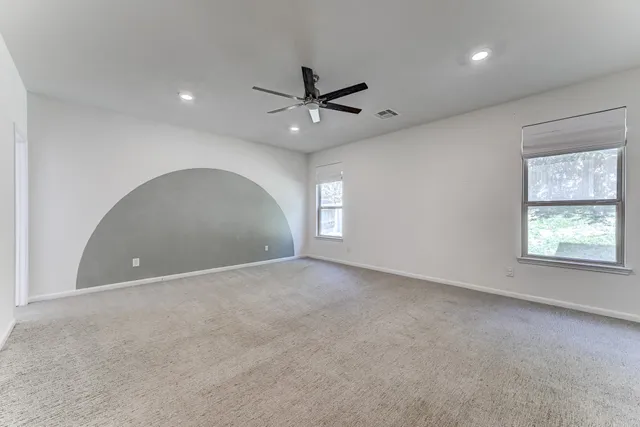 an empty room with a window and a ceiling fan