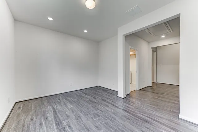 a view of an empty room with wooden floor and closet