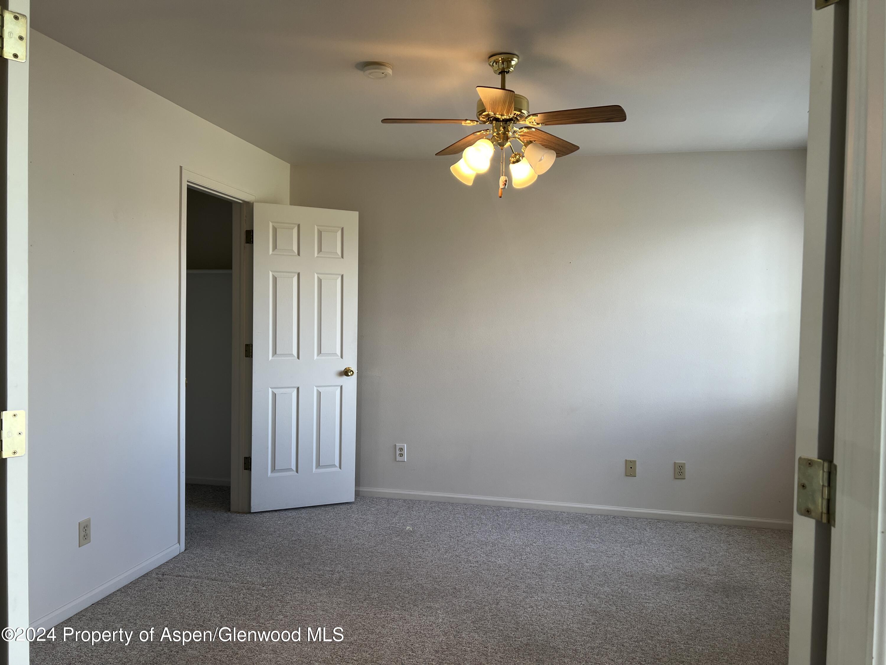 424 Lind Avenue Rifle, CO 81650 - Photo 9 of 24 an empty room with a chandelier fan and windows